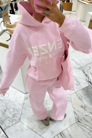 Woman wearing a pink hoodie with 'Kenzen' branding on a white background